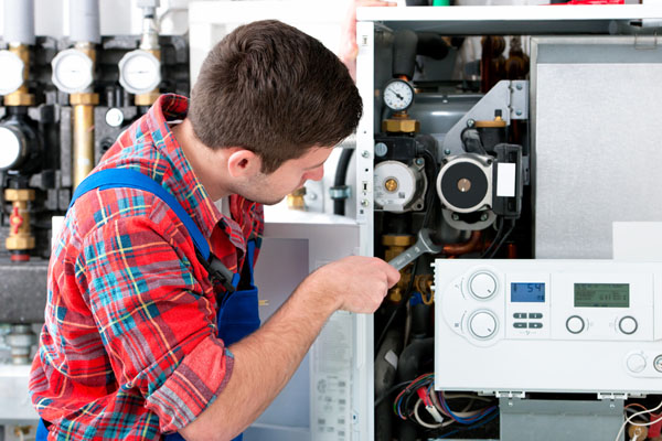 HVAC technician inspecting and repairing boiler controls in Arvada