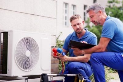 ac-installation-in-claremont-ca HVAC technicians reviewing an outdoor air conditioning unit in Arvada, CO